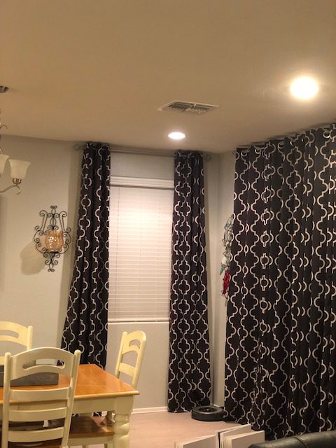 SelectBlinds White Smooth 2 inch Premium Faux Wood Blinds under grommet drapes in living room