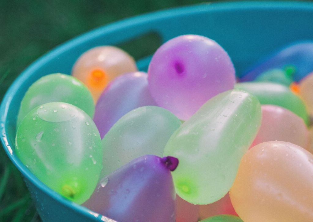 Colorful water balloons in a blue tub.