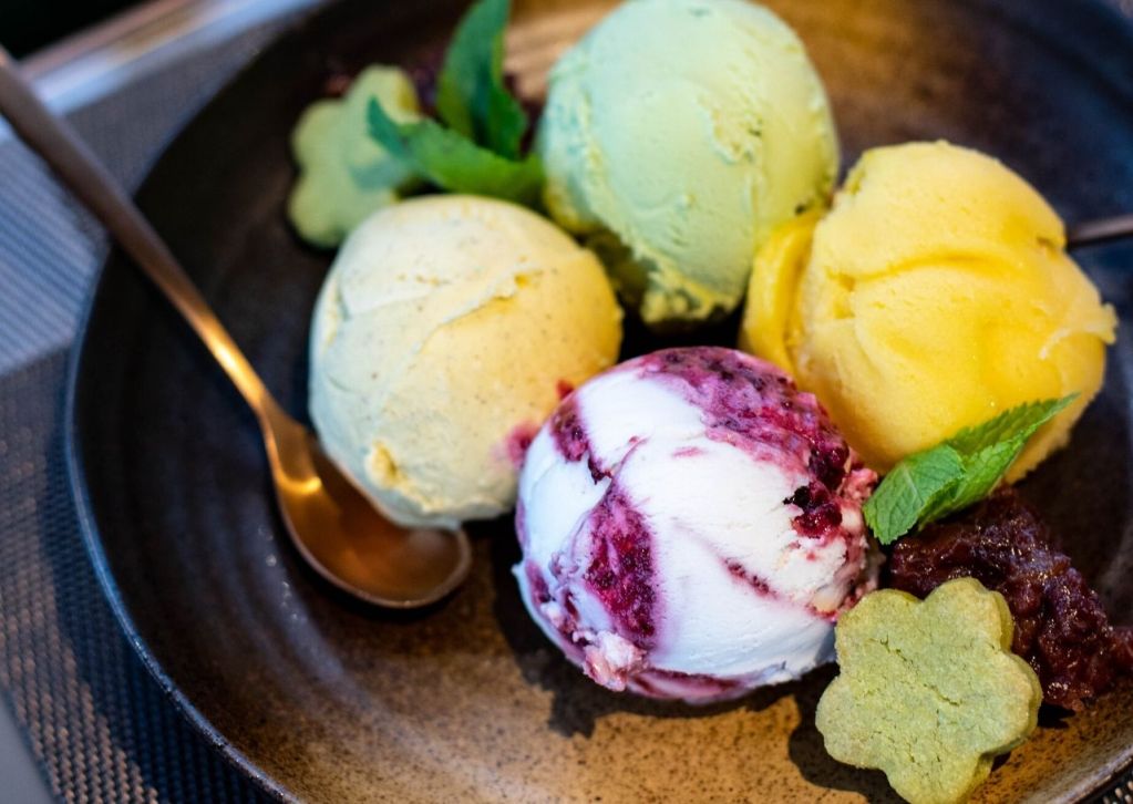 Four flavors of homemade sorbet on a black plate.