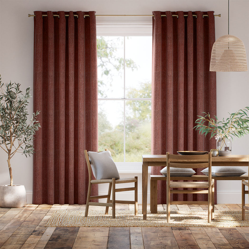 Red curtains hung up in living room with big window, dining table and chairs, plants.